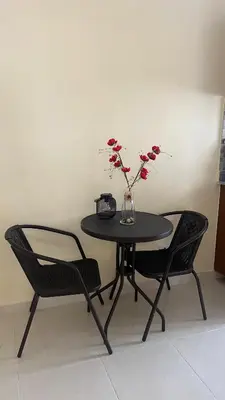 a black table with two chairs and a vase with flowers at Olas del caribe DR in Santo Domingo