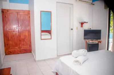 a room with a bed and a television and towels at Aparta Hotel Azzurra in Boca Chica