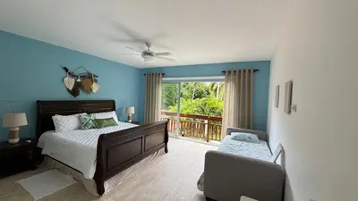 a bedroom with blue walls and a bed and a balcony at Portillo Beach Family House in El Limón