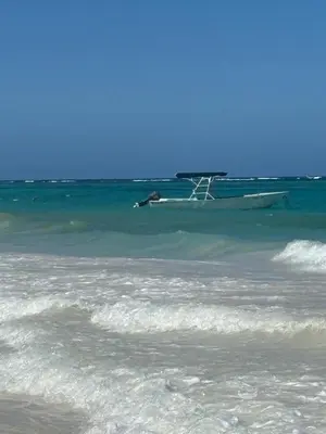 a boat floating in the water on a beach at Apartment Punta Cana Oasis ONA Residences in Punta Cana