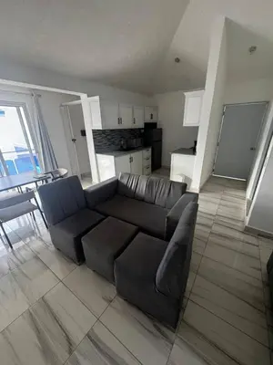 a living room with a black couch and a kitchen at El Legendario in Sosúa