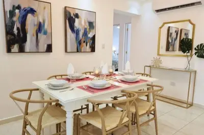 a dining room with a white table and chairs at Stylish 3BR Condo, Full AC, Wi-Fi in Santo Domingo