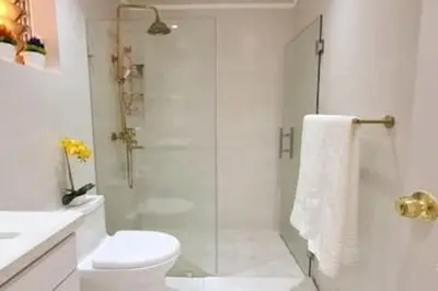 a white bathroom with a shower and a toilet at Stylish 3BR Condo, Full AC, Wi-Fi in Santo Domingo