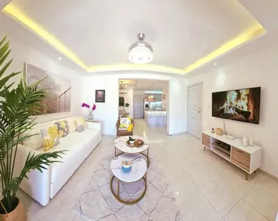a living room with a white couch and a tv at Stylish 3BR Condo, Full AC, Wi-Fi in Santo Domingo