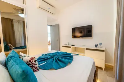 a bedroom with a bed with blue pillows on it at Vista Family Garden Suite Pool front 2 Bdrms in Punta Cana