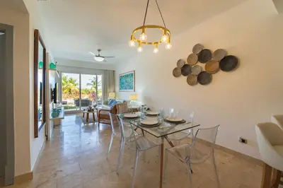 a dining room and living room with a table and chairs at Vista Family Garden Suite Pool front 2 Bdrms in Punta Cana