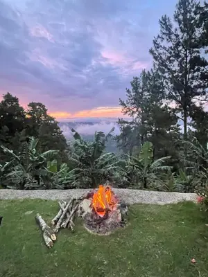 a fire pit in the grass with a view at Eco Domes Couples Getaway - Waterfall and Mountain Views in Jarabacoa