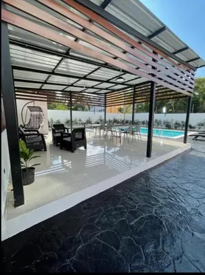 a pavilion with chairs and tables and a pool at Tranquilo y acogedor in Santiago de los Caballeros