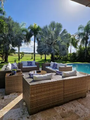 a patio with wicker furniture and a pool with palm trees at Villa Polo Luxury Villa in Casa de Campo, La Romana in La Romana