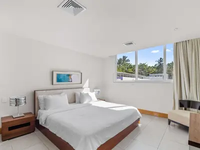 a bedroom with a bed and a chair and a window at Stay at Ultravioleta Cabarete Beachfront Apartments by EvoKey in Cabarete