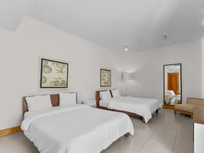 two beds in a room with white walls at Stay at Ultravioleta Cabarete Beachfront Apartments by EvoKey in Cabarete