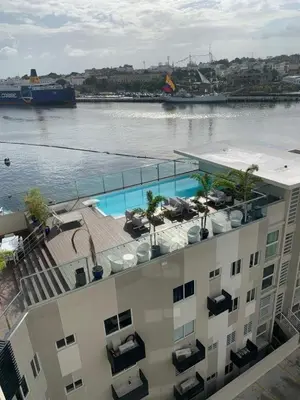 a building with a swimming pool next to a body of water at Apartment5Start in Santo Domingo