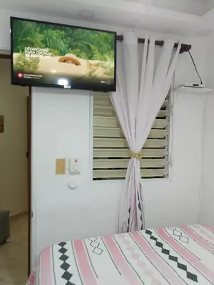 a room with a bed and a television on a wall at Apartaestudio en el malecón y cerca de playas in San Felipe de Puerto Plata