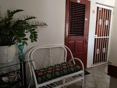 a white chair sitting in a room with a door at Apartaestudio en el malecón y cerca de playas in San Felipe de Puerto Plata