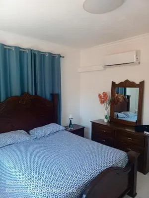 a bedroom with a bed with blue curtains and a mirror at Hogar cerca de la playa in Punta Cana
