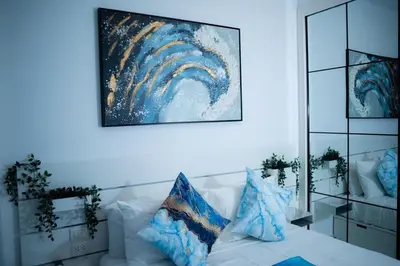 a white bed with blue pillows and a painting on the wall at Ocean Blue at Cana Rock Star in Punta Cana