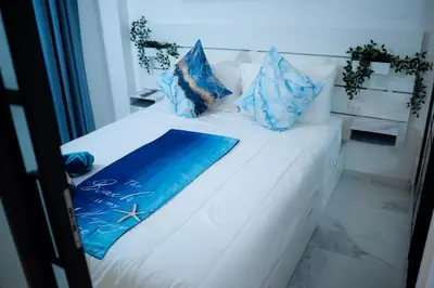 a white bed with blue pillows on it at Ocean Blue at Cana Rock Star in Punta Cana