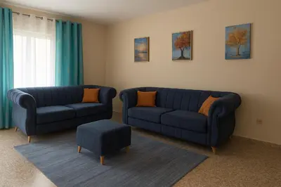 a living room with two blue couches and a stool at Relaxing and Serene Guest Room in Cancino