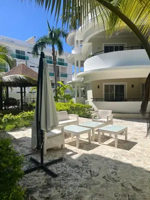 an umbrella and benches in front of a building at Tu refugio en Los Corales Punta Cana, wifi rápido y piscina in Punta Cana