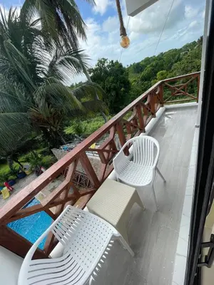 a balcony with two white chairs and a pool at Rancho paraíso escondido in San Pedro de Macorís