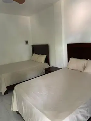 two beds in a hotel room with white sheets at Rancho paraíso escondido in San Pedro de Macorís
