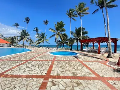 a resort with a pool and palm trees on the beach at comfortable apartment in La Puntica de Juan Dolio