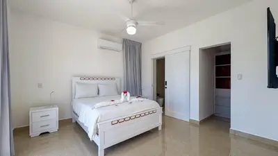 a white bedroom with a white bed and a dresser at Sosua Ocean Village - Villas Marinas 27B in Sosúa