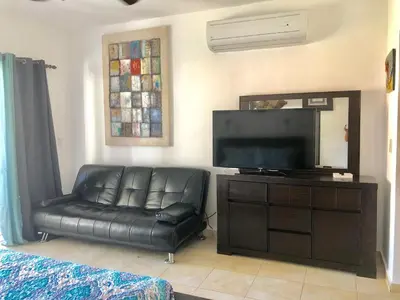 a living room with a black leather couch and a flat screen tv at Cadaques Bayahibe Family Apts in Bayahibe