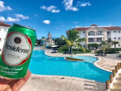 a person holding a can of beer in front of a pool at Cadaques Bayahibe Family Apts in Bayahibe