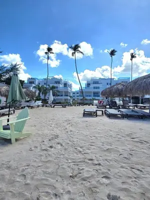 a beach with chairs and umbrellas and palm trees at Beautiful 2 bedroom apartment on the beach in Punta Cana