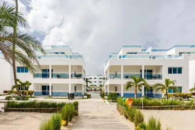 a row of white buildings on the beach with palm trees at Beautiful 2 bedroom apartment on the beach in Punta Cana