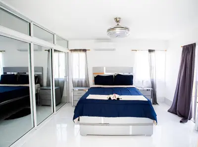 a bedroom with a bed with blue sheets and mirrors at Apartment with Pool, Cofresi in San Felipe de Puerto Plata