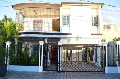 a white house with a gate in front of it at Casa Bayaguana Real in Bayaguana