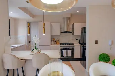 a kitchen with white cabinets and a table and chairs at Luxstay SDQ in Santo Domingo