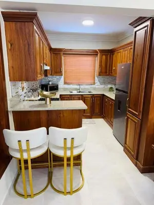 a kitchen with wooden cabinets and white chairs in it at Punta Cana Apartment Tropical Escape near Beach in Punta Cana