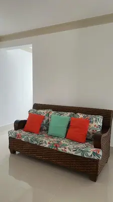 a brown wicker couch with four colorful pillows on it at Cabarete Town House in Cabarete