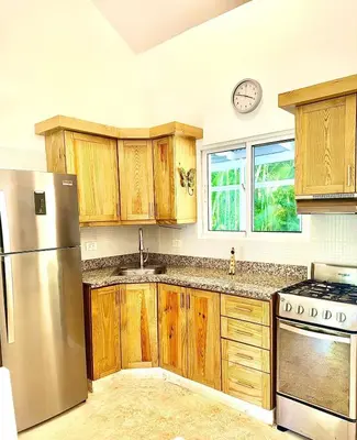 a kitchen with wooden cabinets and a stainless steel refrigerator at Charming 2 bed 2bath villa 77B with private pool in Sosúa