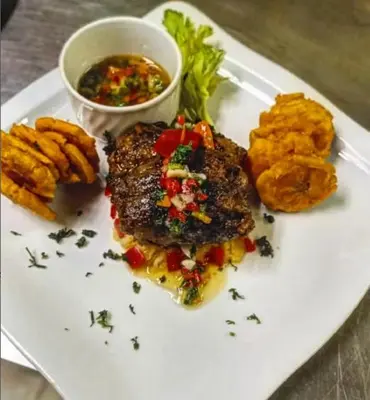 a plate of food with a piece of meat and fries at Hotel Novus Caoba, Confort y calidez en Mao, Valverde