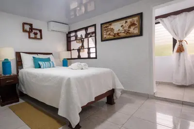 a bedroom with a bed with a white blanket and a window at Puerto Plata Home in San Felipe de Puerto Plata
