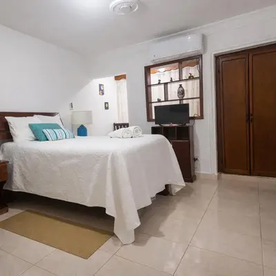 a white bedroom with a bed and a television at Puerto Plata Home in San Felipe de Puerto Plata