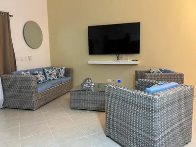 a living room with two wicker chairs and a flat screen tv at Villa 156, 3 bedrooms and 3 bathrooms with private pool in Sosúa