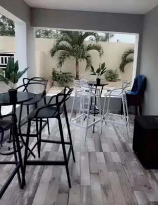a room with tables and chairs and a palm tree at Villa Lujosa en Boca Chica in Cuevas