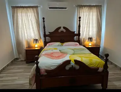 a bedroom with a bed with two night stands and two lamps at Villa Lujosa en Boca Chica in Cuevas