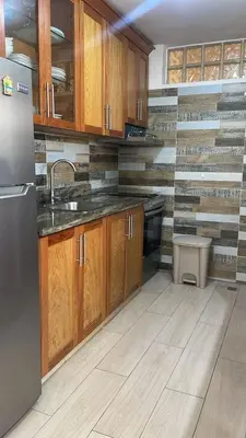 a kitchen with wooden cabinets and a stainless steel refrigerator at Residencial flor Betania in San Pedro de Macorís