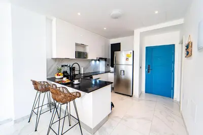 a kitchen with two bar stools and a refrigerator at Vista Jade Apartamento 2 Hab Vista Picina y Golf in Punta Cana