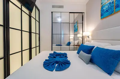 a bedroom with a large white bed with blue pillows at Directo piscina jardín terraza @ Cana Rock in Punta Cana