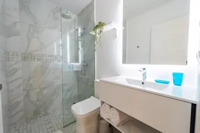 a white bathroom with a sink and a shower at Directo piscina jardín terraza @ Cana Rock in Punta Cana
