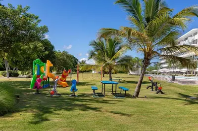 a playground in a park with a palm tree at Single Loft Best Pool Views! Cana Rock Star G-205 in Punta Cana