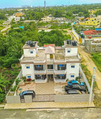 a large white house with cars parked in front of it at Cozy 2 Bedroom Apartment Boca Chica in Boca Chica