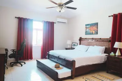 a bedroom with a large bed with red curtains at 4-Suite Tranquil Retreat in Sosua Ocean Village in Sosúa